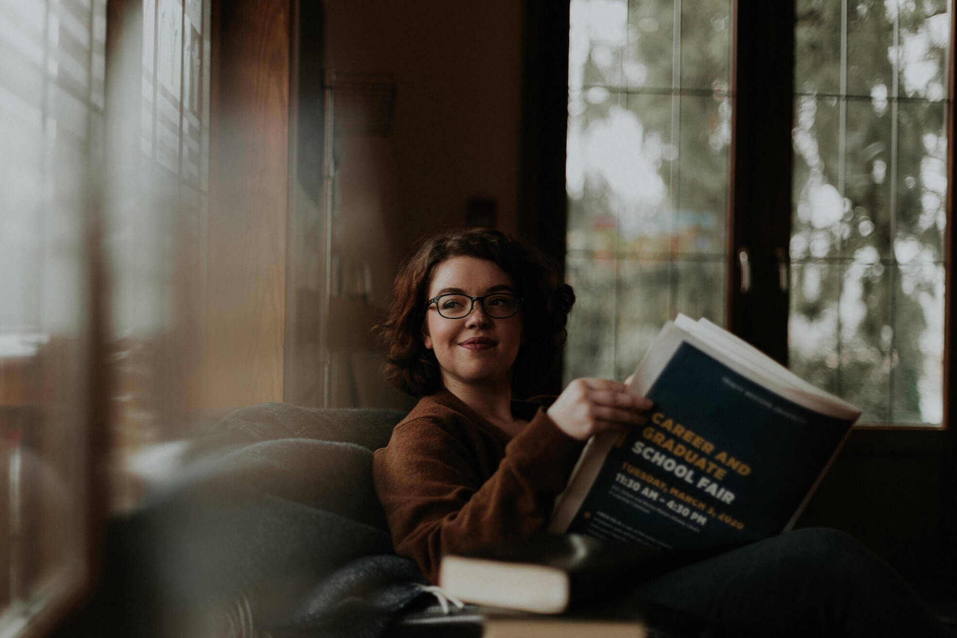 woman-reading-book-and-looking-out-a-window